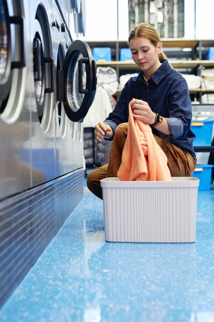 girl-putting-clothes-into-washing-machine-public-laundry_236854-66667